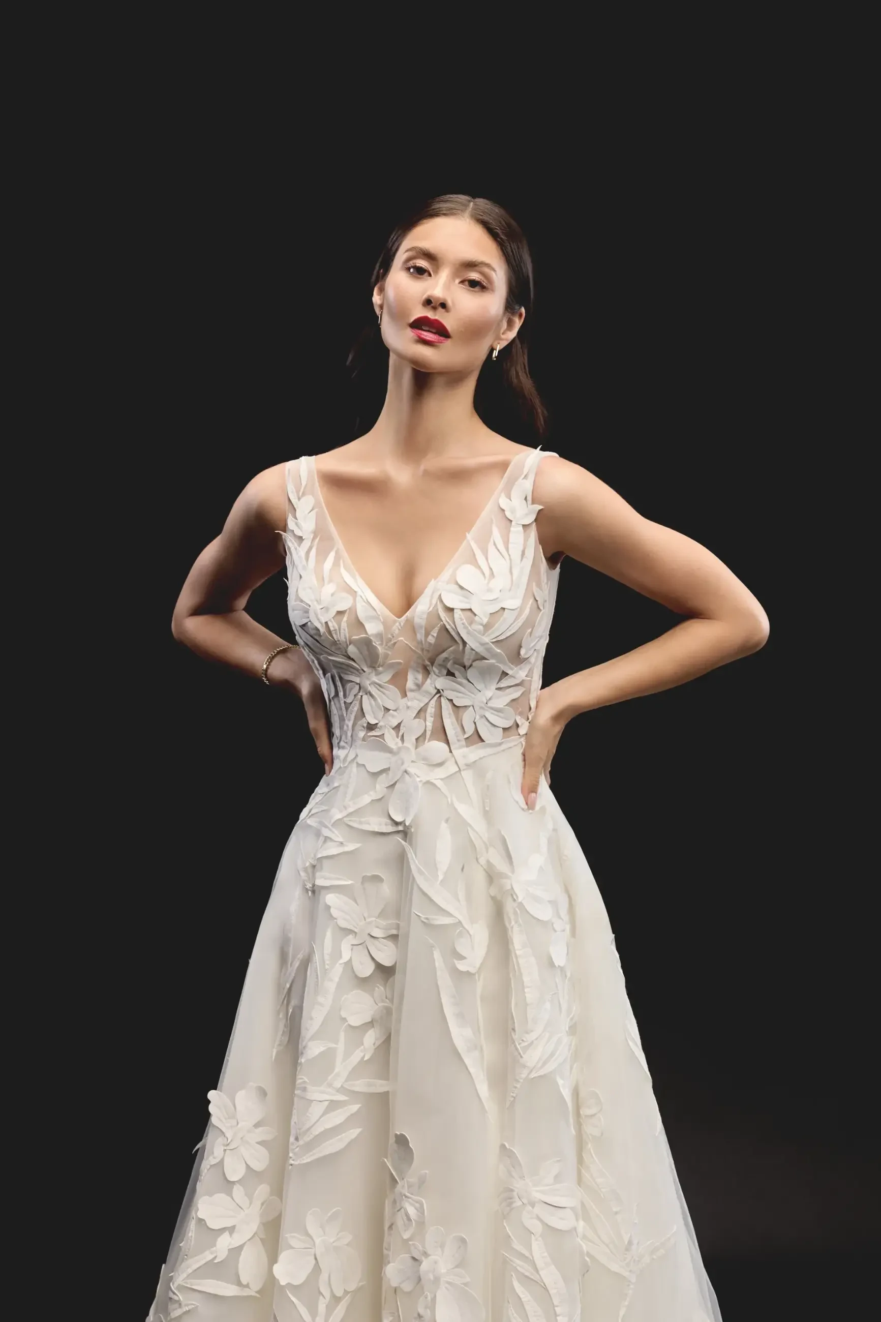 Model is wearing an A-line gown with a V-neckline, sleeveless tulle bodice, and 3D floral appliqués with a thigh-high slit.