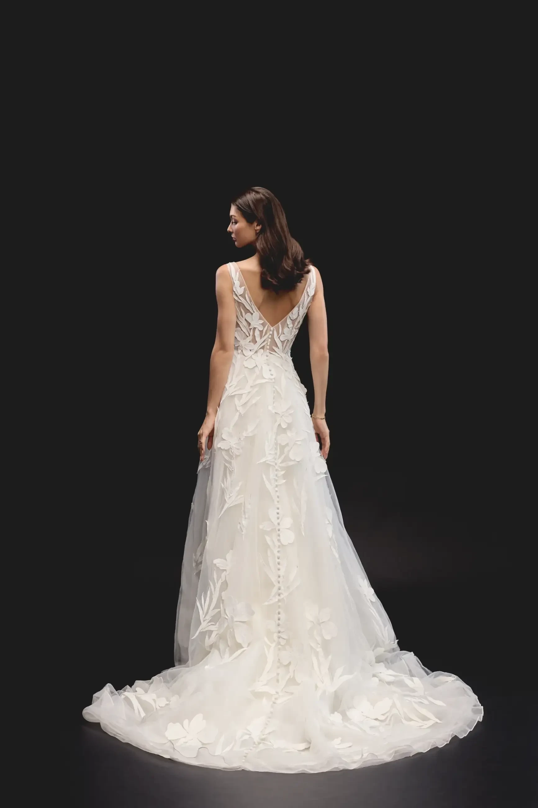 Model is wearing an A-line gown with a V-neckline, sleeveless tulle bodice, and 3D floral appliqués with a thigh-high slit.