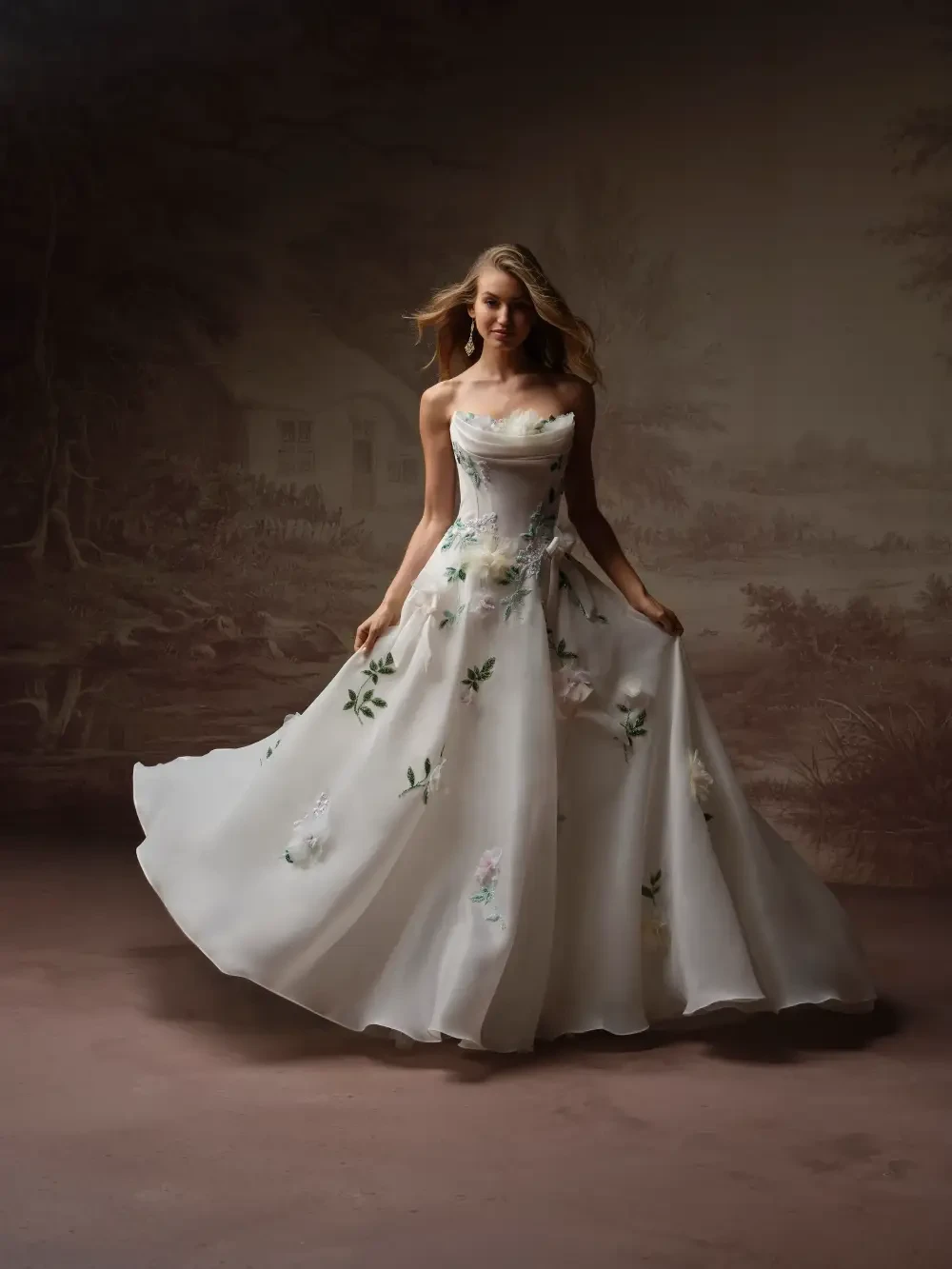 A woman in a flowing white dress adorned with floral patterns, standing gracefully in a softly lit setting.