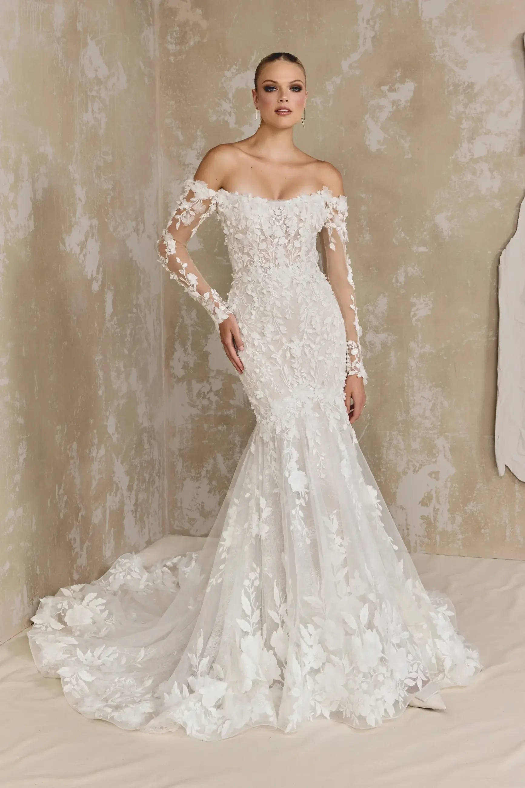 Model is wearing an off the shoulder lace mermaid bridal gown