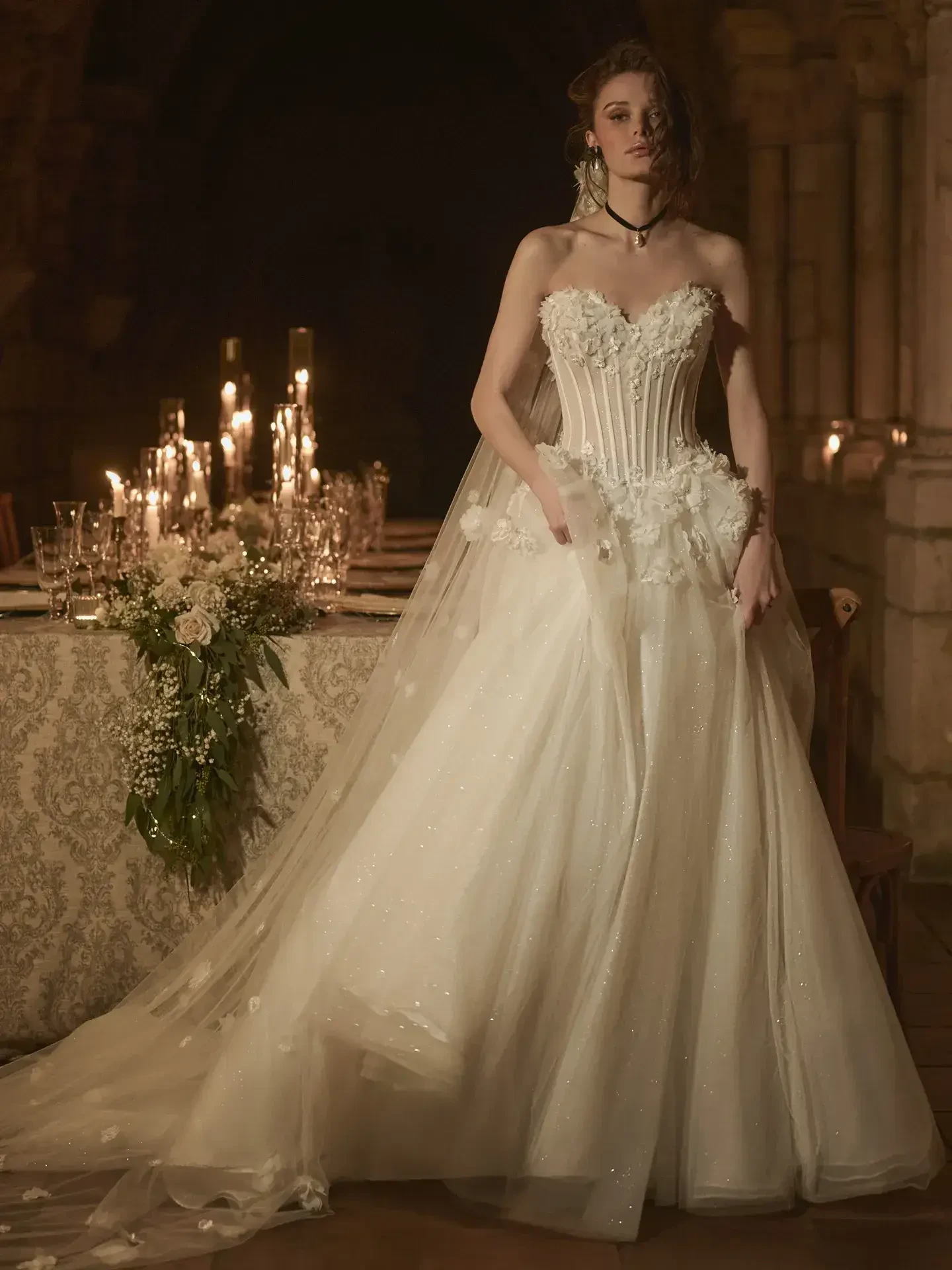 Model is wearing a Sottero and Midgley Wesley gown, a dramatic ballgown with 3-D floral appliqués, exposed boning, and a voluminous skirt.